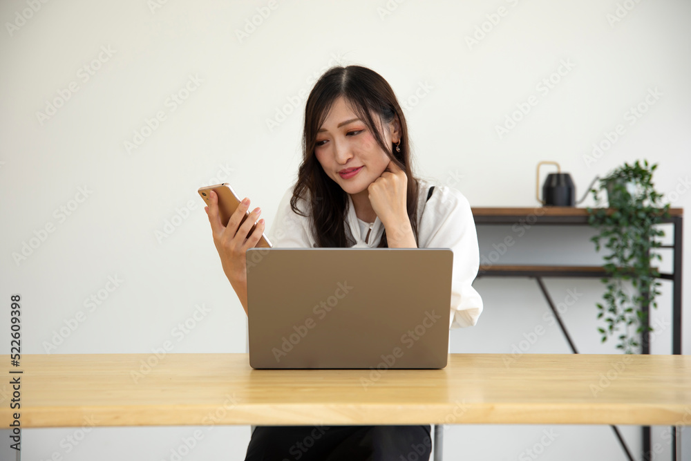 A Japanese woman checking smartphone by remote work in the small office A Japanese woman checking smartphone by remote work in the small office