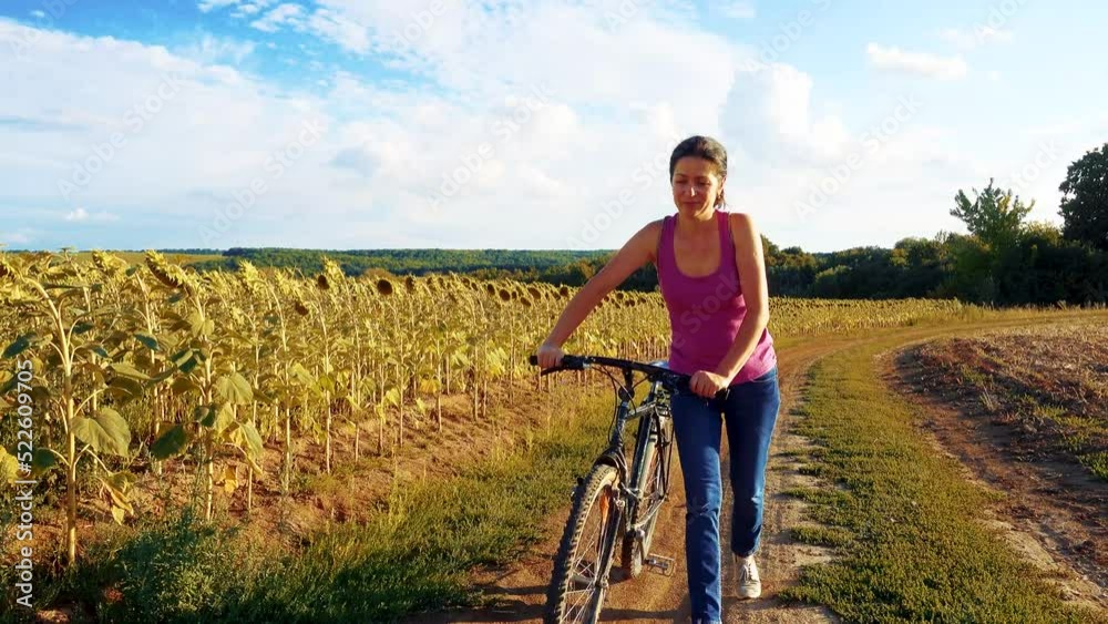 Young happy woman on a bike in the field. The girl takes a bike ride in nature. The concept of happiness, recreation, sports, nature. Young happy woman on a bike in the field. The girl takes a bike ride in nature. The concept of happiness, recreation, sports, nature.