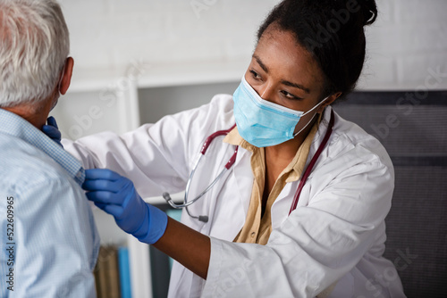 Fotografija Female doctor is examining male elderly patient at clinic