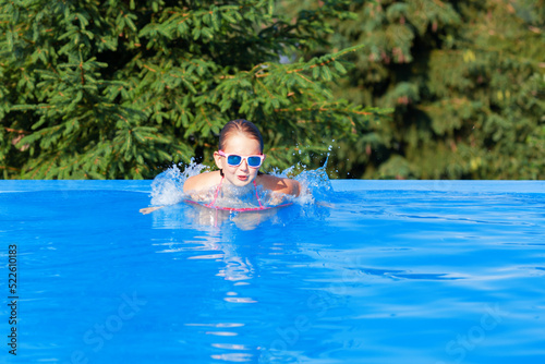 cute girl playing in outdoor swimming pool. Summertime Water Fun.