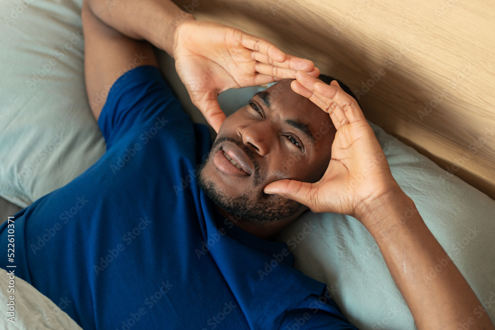 Black Guy Suffering From Headache Lying In Bedroom, Above View