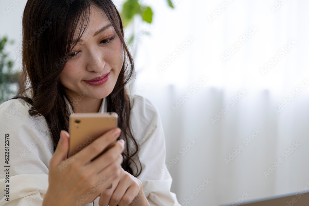 A Japanese woman checking smartphone by remote work in the small office A Japanese woman checking smartphone by remote work in the small office