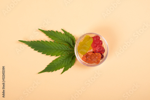 thc jelly candies, cannabis sweets drugs and green leaf on yellow background.
