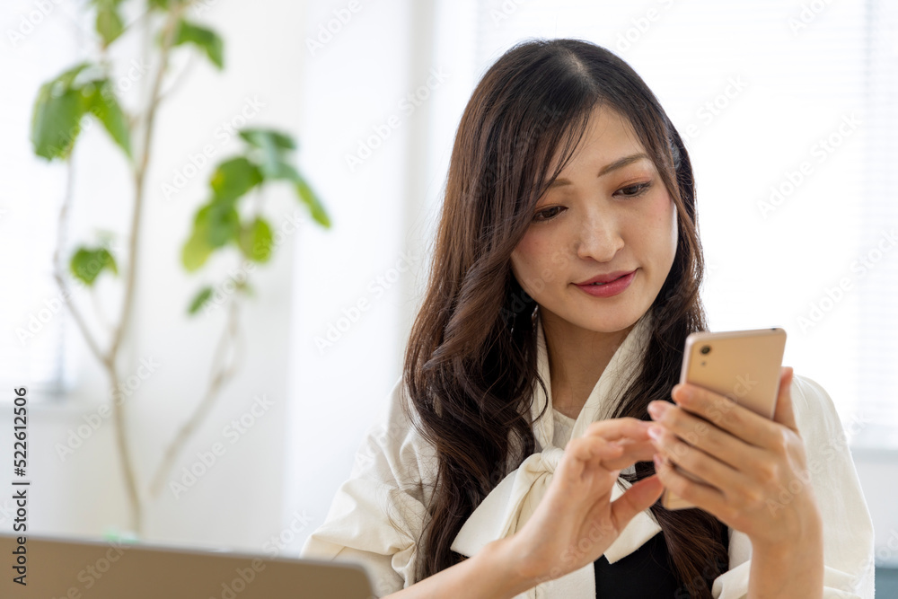 A Japanese woman checking smartphone by remote work in the small office A Japanese woman checking smartphone by remote work in the small office