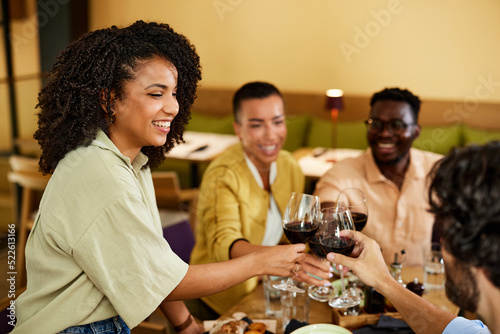 A group of multiracial friends is raising glasses and celebrating the event at the restaurant.