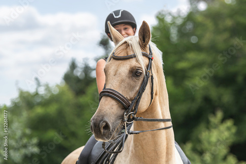 Equestrian scene: A female rider on a palomino kinsky warmblood horse during warm up for dressage training photo