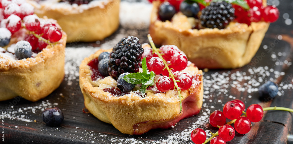 Fruit tart with red currants sprinkled with powdered sugar on a black table Fruit tart with red currants sprinkled with powdered sugar on a black table