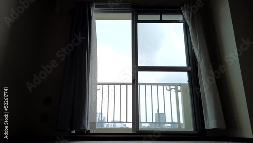 A skyscraper seen from the window of vacant studio apartment and curtains swaying in the wind. timelapse.