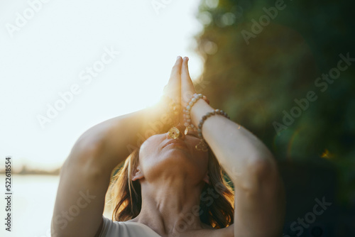 Obraz na płótnie A yogi woman holds her hands in a namaste position and prays while exercising yoga on the dock near the river in nature