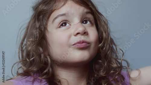 Portrait of a cute toddler girl making funny faces. 4K footage. photo