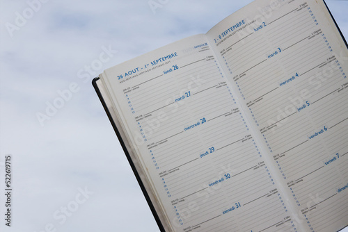 Pages of an agenda in French, English, Spanish, Italian and German with the cloudy sky in the background