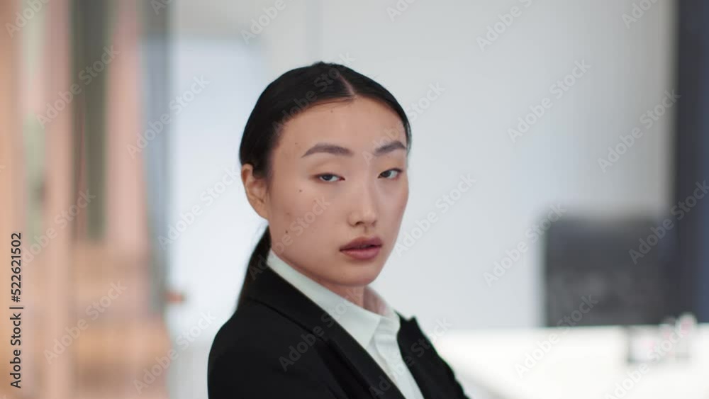Professional young confident asian business lady turning face to camera and looking seriously, standing at office Professional young confident asian business lady turning face to camera and looking seriously, standing at office