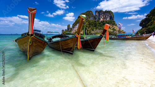 Three long tail boats await tourists on the beautiful islands and emerald crystal clear waters of Krabi, Thailand. © sippakorn