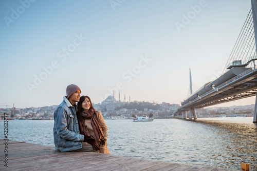 Canvas Print young couple relaxing on the side of bosphorus during sunset