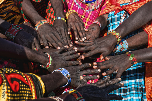 Fotografie, Obraz Hands of Maasai Mara tribe people putting together showing their bracelet