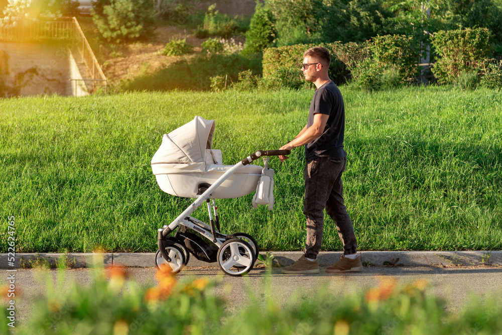 a young father with a white stroller walks around the city. A man walks with his baby in a stroller a young father with a white stroller walks around the city. A man walks with his baby in a stroller