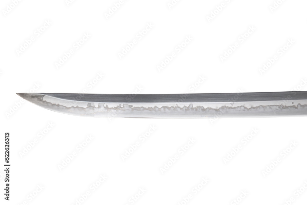 Japanese sword blade (made in China) on white background. Soft focus. The wavy pattern on the blade edge is a line of hardness that a blacksmith makes so that the blade doesn't break. Japanese sword blade (made in China) on white background. Soft focus. The wavy pattern on the blade edge is a line of hardness that a blacksmith makes so that the blade doesn't break.
