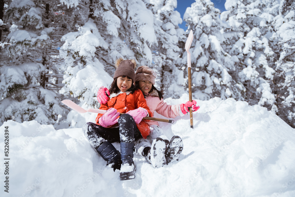 Fototapeta premium two girl playing with snow. asian little sister enjoy their time in snowy winter together