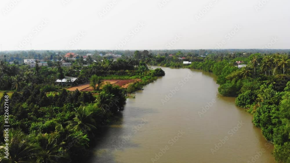 Aerial Rising Up View of Mekong Delta River Region in Vietnam Asia, Vast Long Brown Water Canal Waterway Riverside, Riverbank Surrounded by Local Village, Agricultural Lands Vegetation and Rural Homes Aerial Rising Up View of Mekong Delta River Region in Vietnam Asia, Vast Long Brown Water Canal Waterway Riverside, Riverbank Surrounded by Local Village, Agricultural Lands Vegetation and Rural Homes