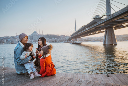 Fototapeta happy asian family sitting on the side of bosphorus looking at beautiful sunset