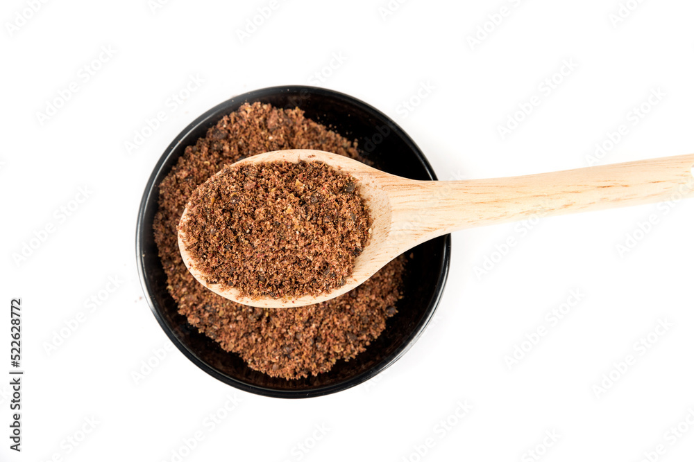 Ground dried sumac berry powder in a black bowl and a wooden scoop Ground dried sumac berry powder in a black bowl and a wooden scoop