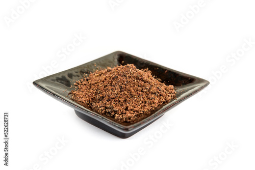 Ground dried sumac berry powder on a black ceramic plate