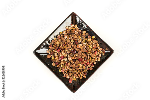 Whole dried sumac berries in a black ceramic plate over white top down