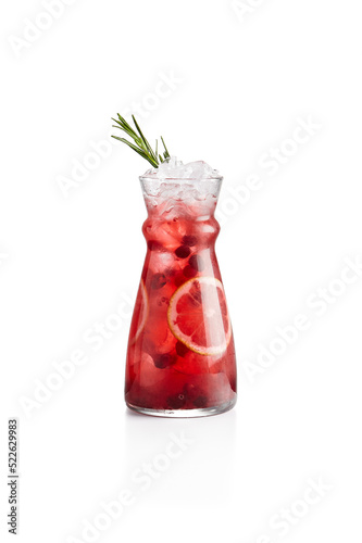 Cranberry lemonade with orange and rosemary in jug. Cranberry cocktail on white background. Cold cocktail in winter bar menu. Non alcoholic drinks. Lingonberry drink.