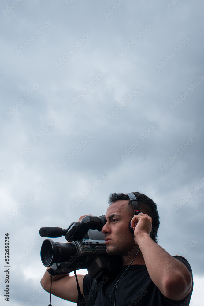 Obraz premium Man filming with a big video camera in a cloudy day