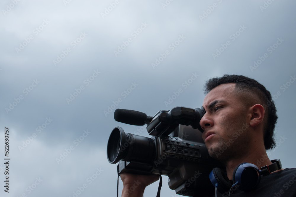 Man filming with a big video camera in a cloudy day