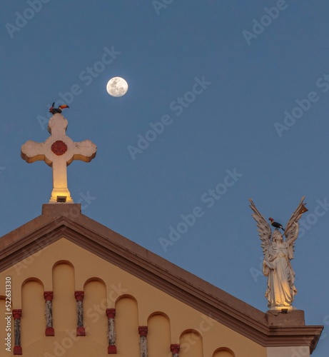 the moon and toucans perched on the Catholic Church of Nossa Senhora da Abadia in Uberaba, Minas Gerais photo