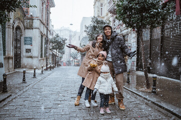 happy asian family traveling in beautiful city during snow fall winter in turkey