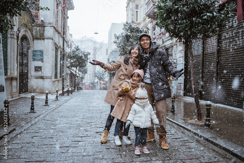 happy asian family traveling in beautiful city during snow fall winter in turkey