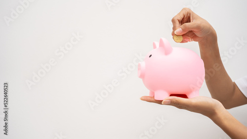 Image of hand of man putting coin into piggy bank.Businessman put money into the piggy bank.Saving for retirement ,Life Insurance ,Free space place for text ,Isolated ,Investor concept.