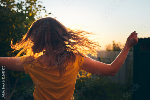 A girl tosses her long beautiful hair in the sun. The concept of hair care and healthy hair. Front view.