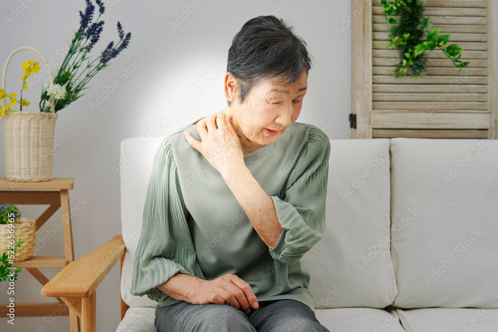 自宅で肩こりを感じるシニア女性 自宅で肩こりを感じるシニア女性