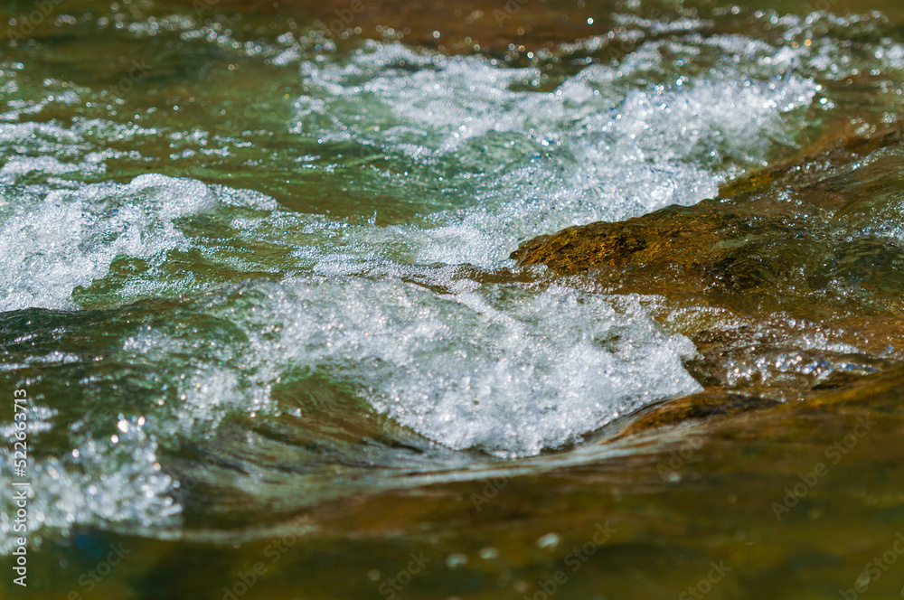 A closeup of rocks in a rapid on the Guadalupe River in the Texas Hill Country. with the water flowing and churning making a backdrop or environmental example image with space for text. A closeup of rocks in a rapid on the Guadalupe River in the Texas Hill Country. with the water flowing and churning making a backdrop or environmental example image with space for text.