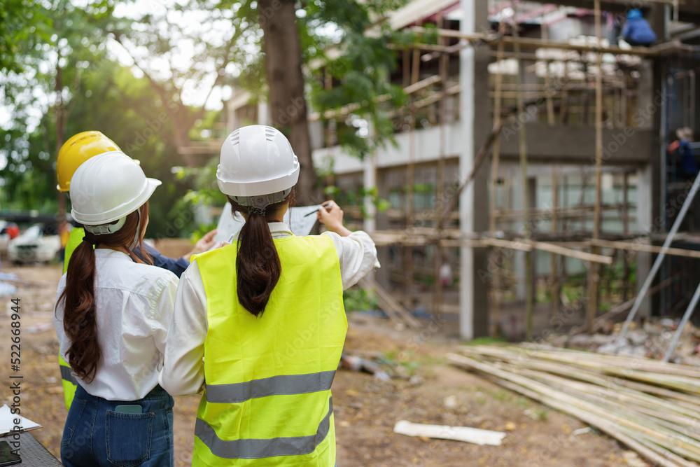 Structural engineer and architect discussing and working with blueprints at the outdoors construction site Structural engineer and architect discussing and working with blueprints at the outdoors construction site