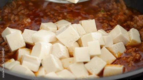 Cooking mapo tofu. Stir-frying tofu with hot spicy sauce in a pot at home. photo