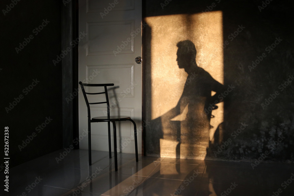 The shadow of a man sitting in a chair on the wall in the room.