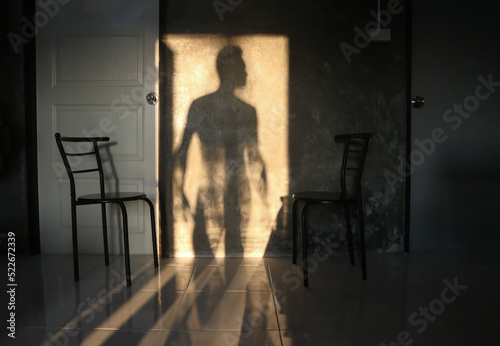 The shadow of the man stood at the door on the wall of the room.