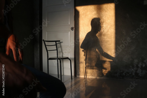 The shadow of a man sitting in a chair on the wall in the room.