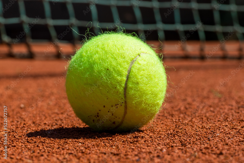 Symbolbild Tennis: Nahaufnahme von einem Tennisball auf einem Sandplatz