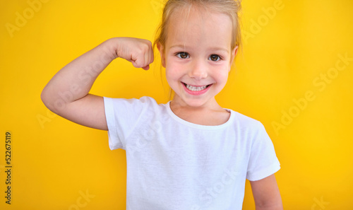 Strong preschool little girl showing flexing her arm muscles smile isolated 