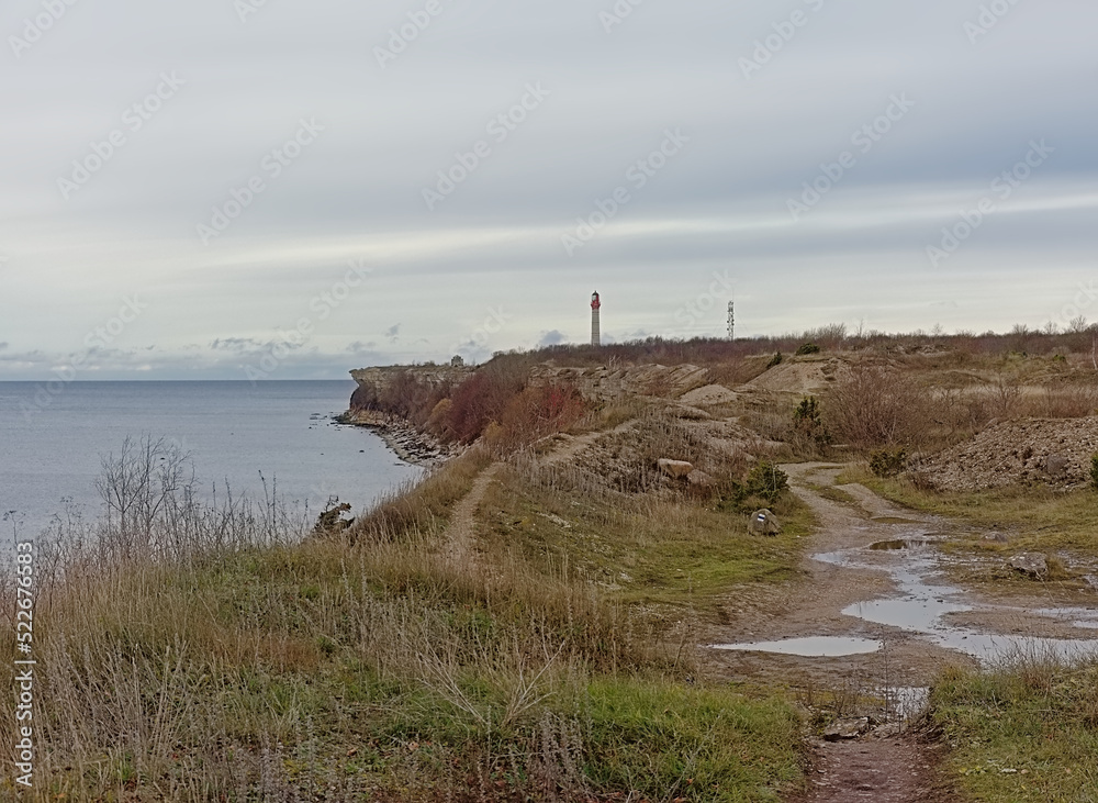 Hiking trail along the  cliffs on the Baltic sea coast of Pakri Peninsula, Paldiski, Estonia, with lighthouse in the distance 
