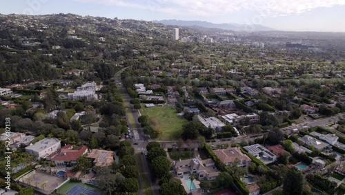 Aerial Panning Shot Of Residential Houses With Swimming Pools In City By Mountains Under Cloudy Sky -  Beverly Hills, California