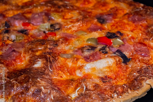 Burnt pizza with ham, mushroom, pepper, cheese on tray in electric oven - close up view, macro. Italian cuisine, homemade bakery, fast food, failure, problem concept