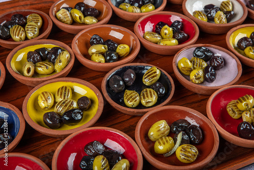 Black and green olives in ceramic bowls on a tray. Olive appetizers on a tray in the restaurant.