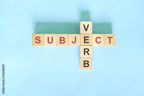 Subject verb agreement concept in English grammar education. Wooden block crossword puzzle flat lay in blue background.