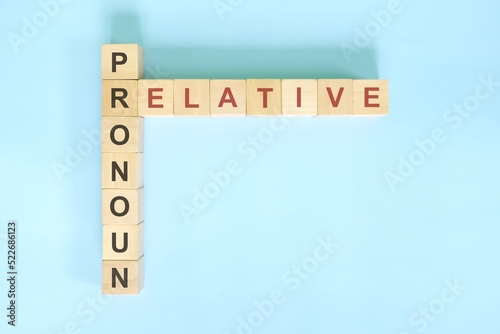 Relative pronoun concept in English grammar education. Wooden block crossword puzzle flat lay in blue background.